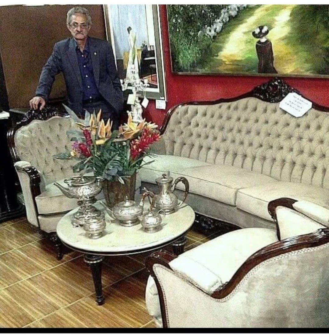 Ademir Verdum ao lado de conjunto de sofá e poltronas capitonê restaurados na Verdum Tapeçaria